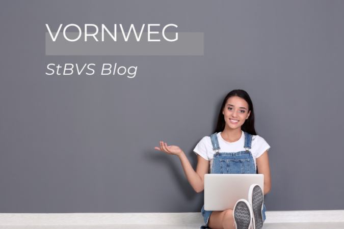Dame mit Laptop sitzt auf dem Boden vor einer grauen Wand mit dem Schriftzug "VORNWEG - StBVS Blog"